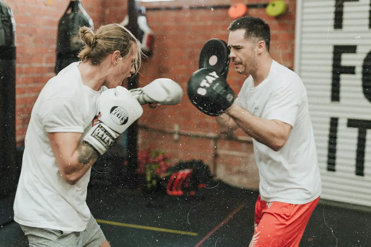 Two everyday blokes doing pad work in a boxing gym